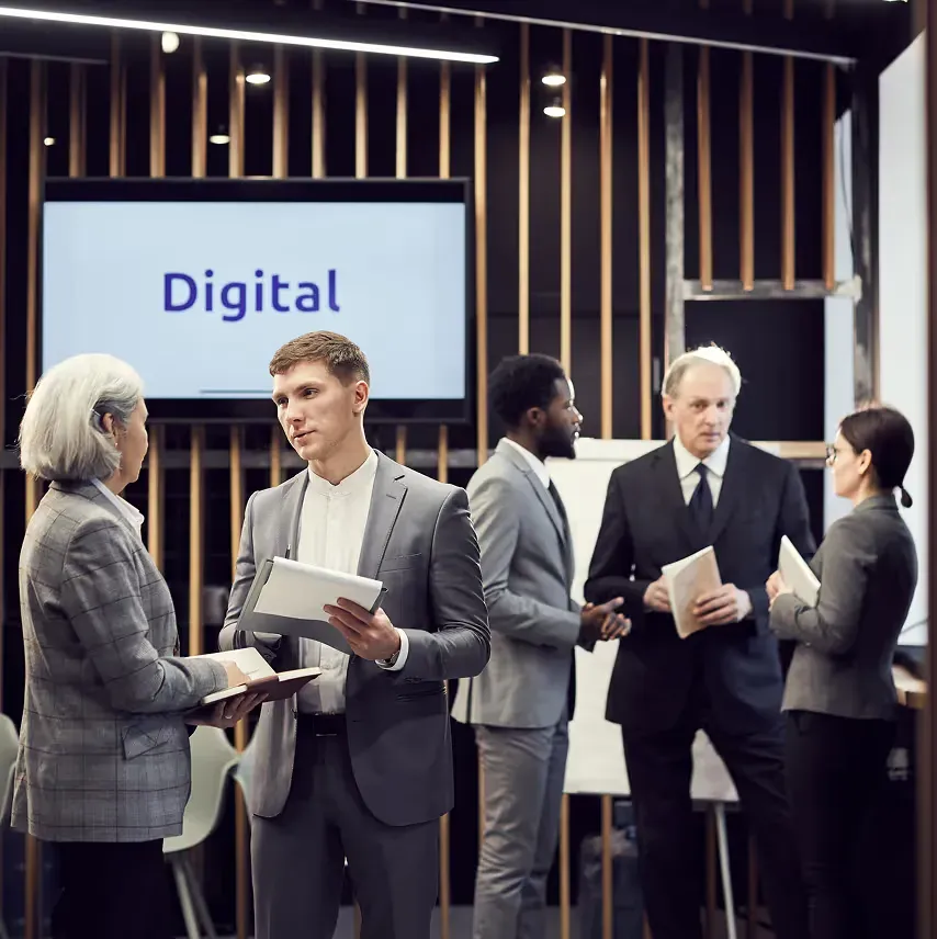 Attendees talking in front of a digital display on the expo floor
